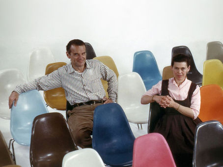 Charles & Ray Eames sentados nas cadeiras coloridas.