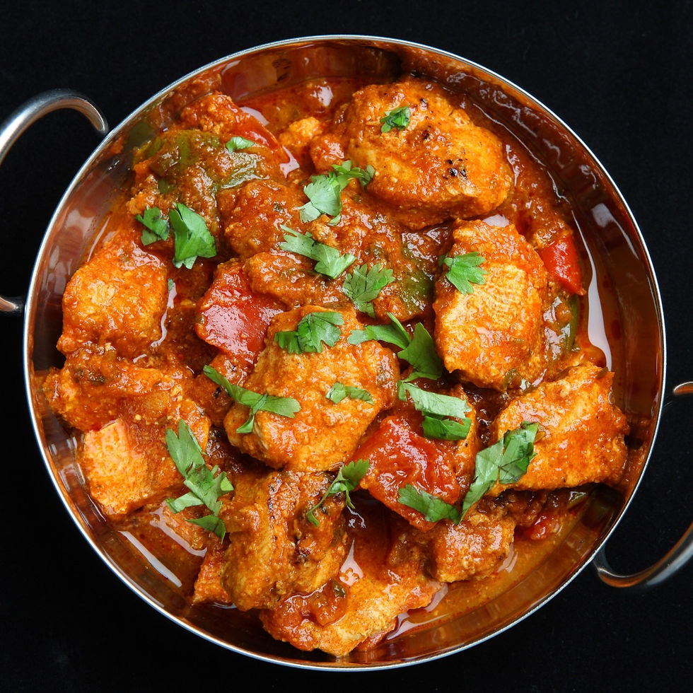 Overhead view of a bowl of chicken curry in a rich, red tomato-based sauce, garnished with fresh cilantro.