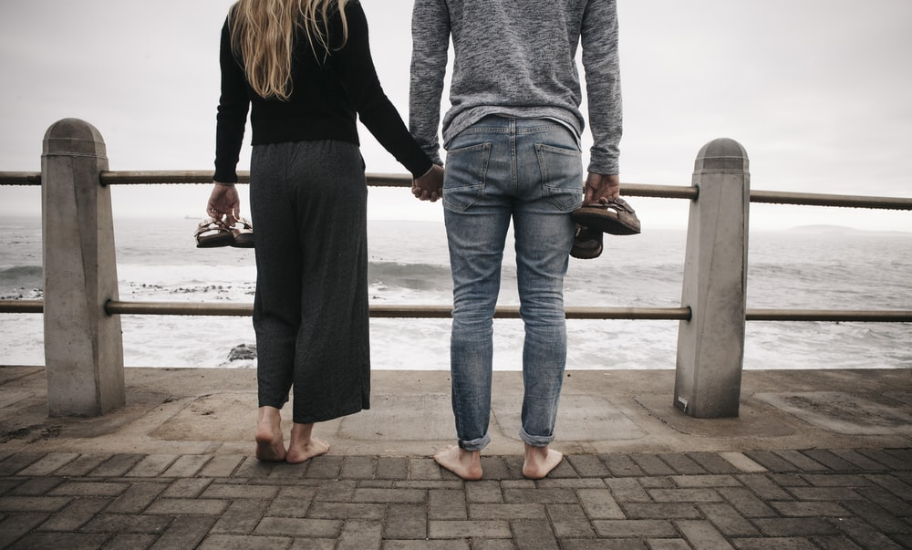 a woman and man standing by the sea