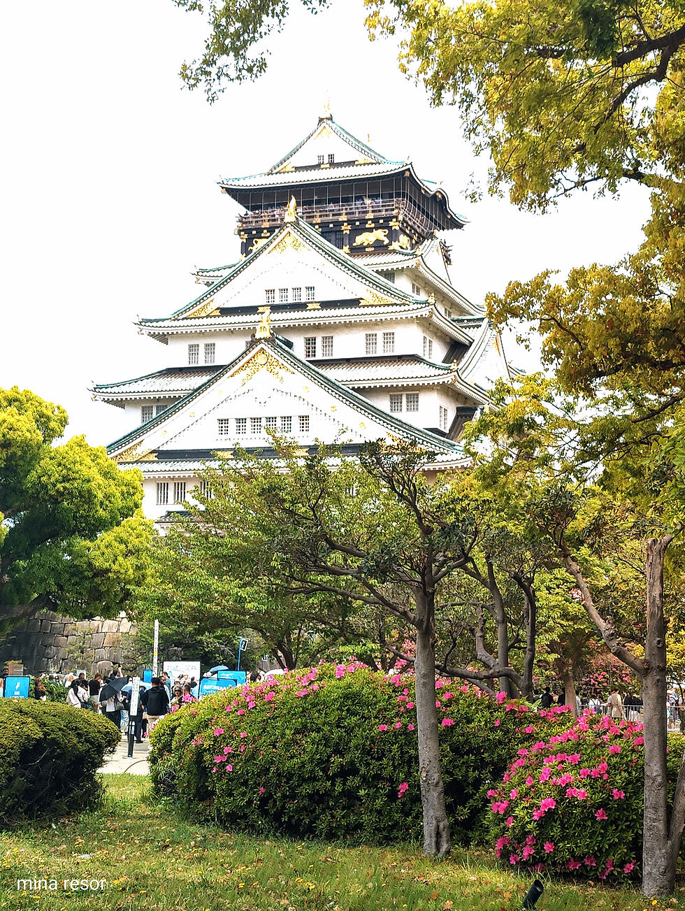 ett slott i japan bakom träden.