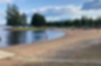 Kalajarven matkailukeskuksen beach uimaranta kesalla puolipilvisella saalla ja uimassa seka hiekkarannalla ihimisia.