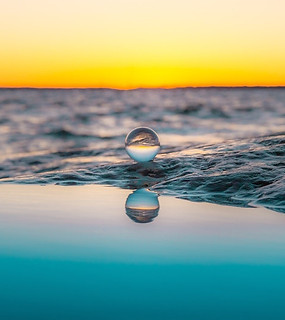 Jarven pinnalla aallokossa vesipisara ja taustalla auringonlasku Virroilla.