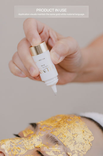 Close-up of serum bottle dispensing product over gold facial mask treatment.