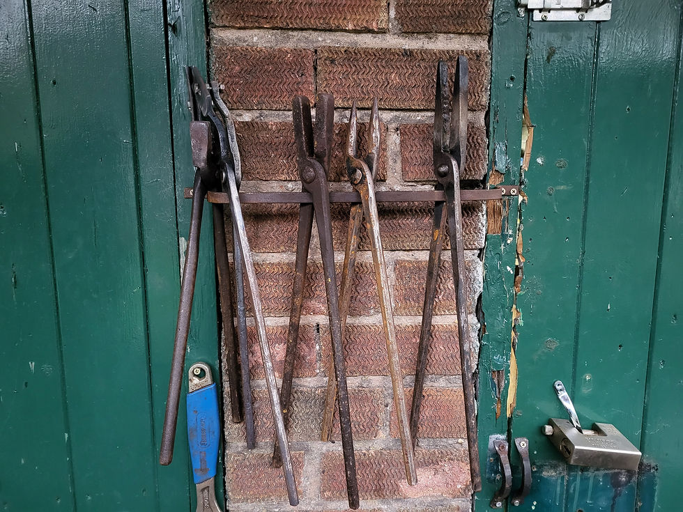 A variety of different tongs for picking up different shaped stock.
