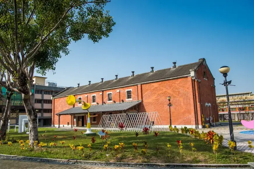 嘉義文創園區紅磚建築外觀，前方有大片綠地與裝置藝術