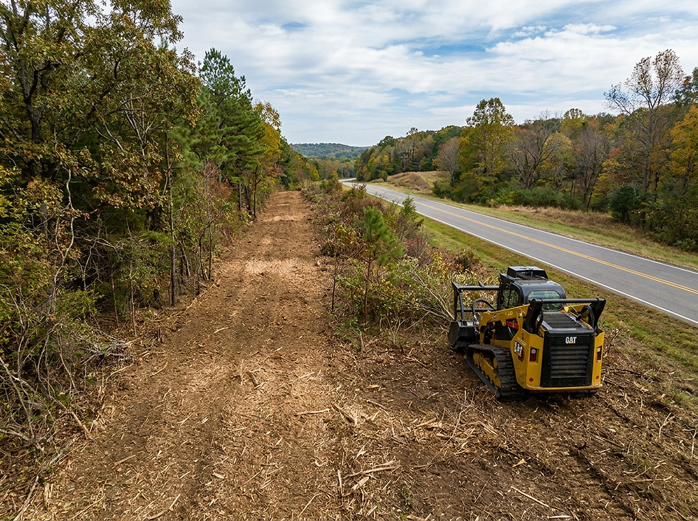 Compact track loader doing land clearing by a highway