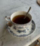 A stunning blue and white teacup with a dark, almost chestnut black tea in it - the pattern is elegant and floral.