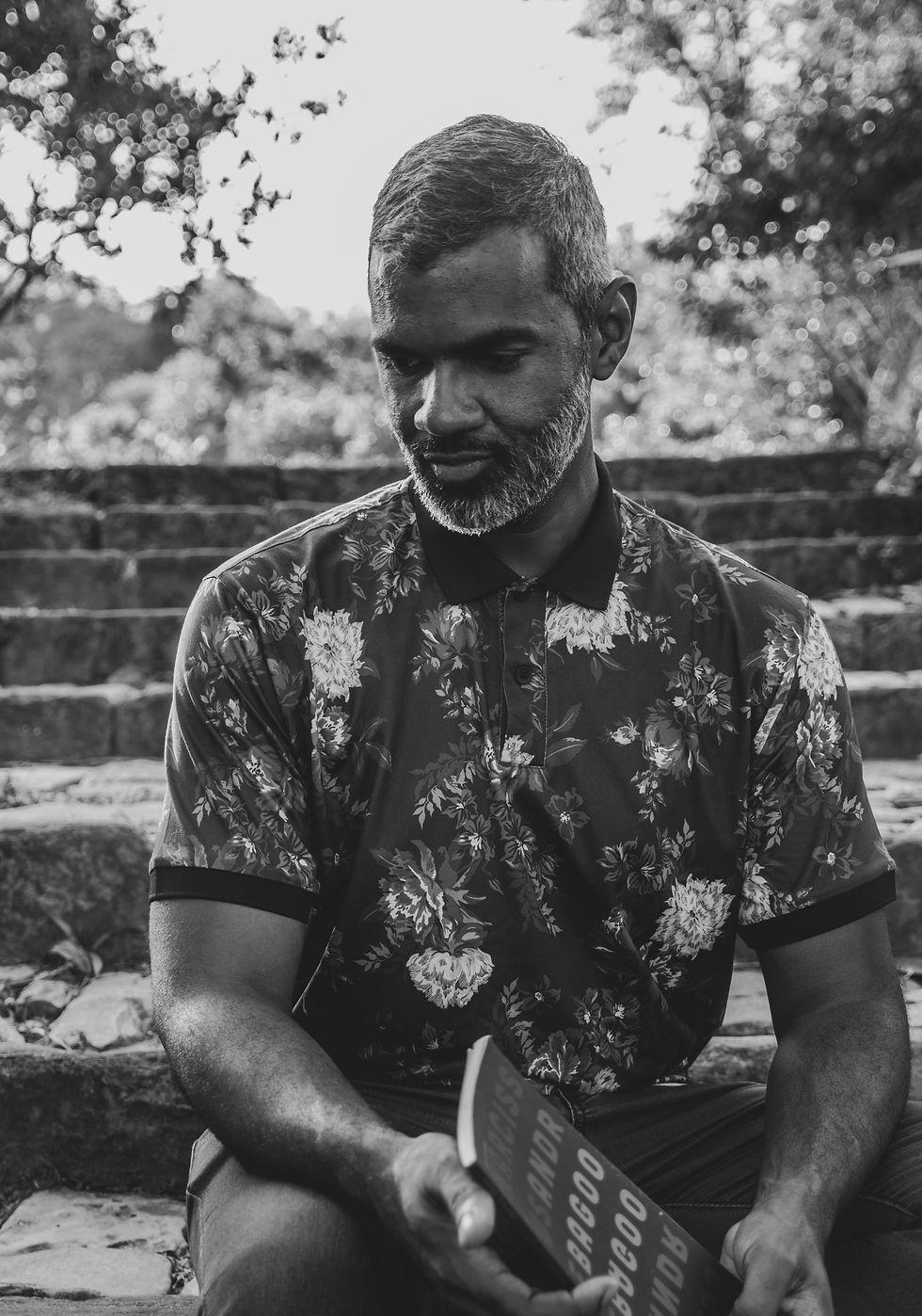 Photo of Andre Bagoo in black and white. Andre is a black man, bearded, wearing a tropical pattern shirt.