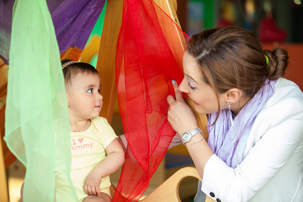 Beautiful ten months baby girl playing with colorful fabrics and her mom. Early stimulatio