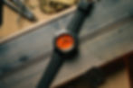 watch with orange dial on work bench with black rubber strap