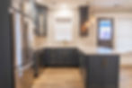 Modern kitchen with dark cabinets and light countertops.