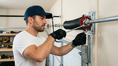 Technician performing garage door repair and service.