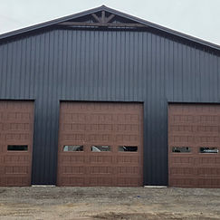 Three wood-grain commercial doors on a dark metal building.
