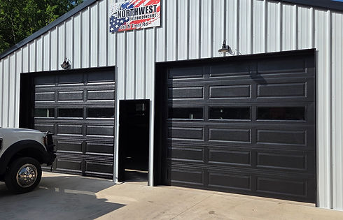 Black commercial garage doors on a white metal building.