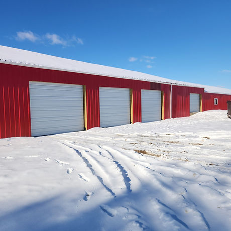 Red commercial building with white sectional doors in snow.