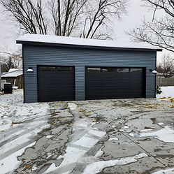Modern blue garage with two black commercial doors in snow.