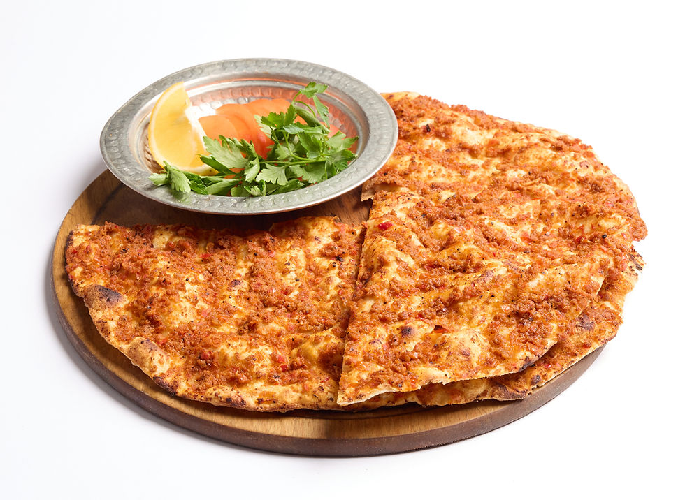 Lahmacun dilimleri tahta tabakta, metal bir kapta limon dilimi, domates ve maydanoz ile sunulmuş, beyaz zemin üzerinde.