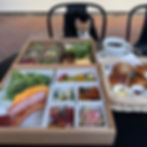 A delicious assortment of breakfast dishes awaits, with a curious pup peeking over the table in anticipation.