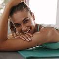 Close up of fit young female lying on exercise mat in gym and smiling. Healthy woman takin