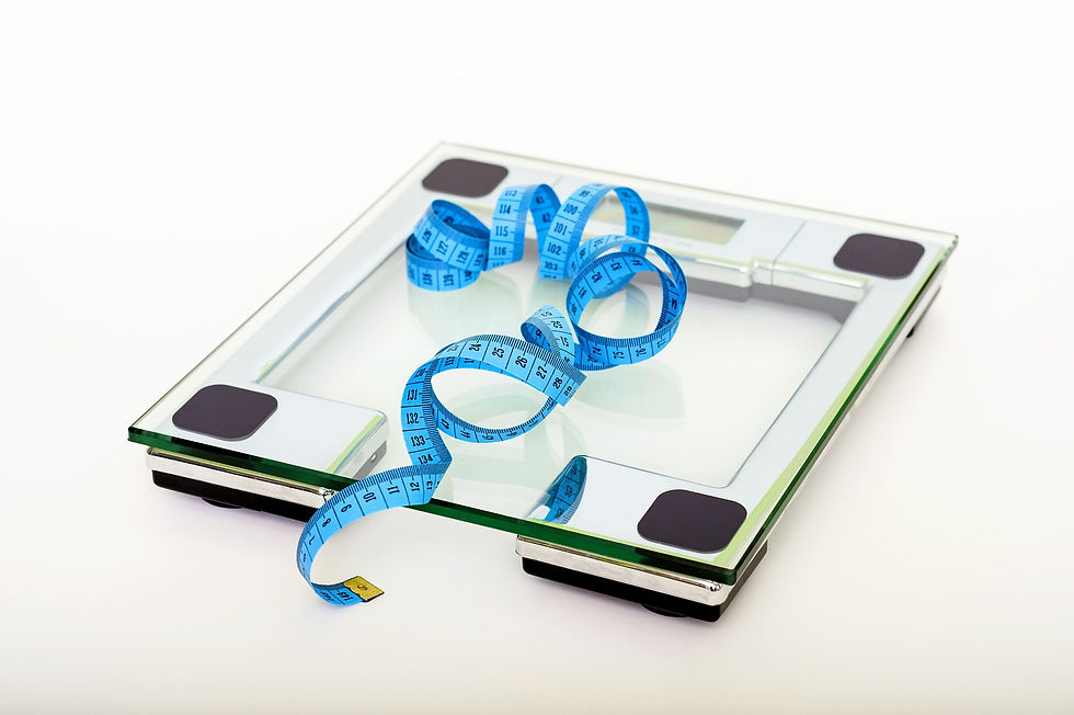Blue measuring tape curled on a glass bathroom scale against a white background