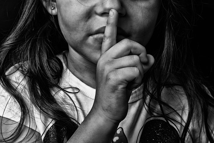 Child with finger over lips for silence