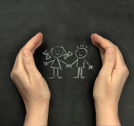 Hands protect children drawn on blackboard with chalk. Concept for International Children'
