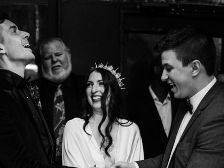 Bride and groom laughing during a close-up magic performance at wedding reception