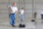 two painters dressed in white shirts and jeans covering floor with paint