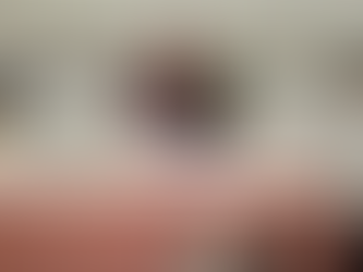 Woman smiling at a book fair table, displaying books and framed signs. Mini Christmas tree, lights, and contact info visible. Warm ambiance.