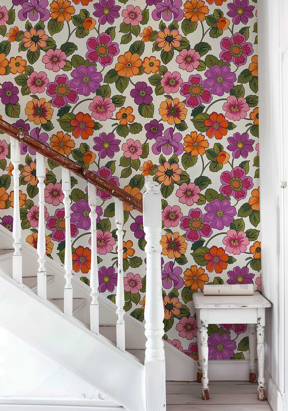 Thumbnail: Fun and vibrant retro floral wallpaper in shades of orange, pink, and purple, with green leaves on a white background.