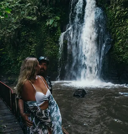 Mann und Frau stehen vor einem Wasserfall in Bali
