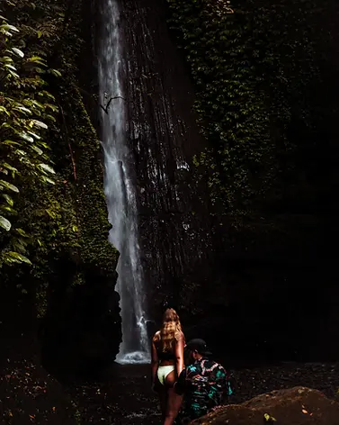 Ein Mann und ein Frau stehen vor einem großen Wasserfall in Lombok