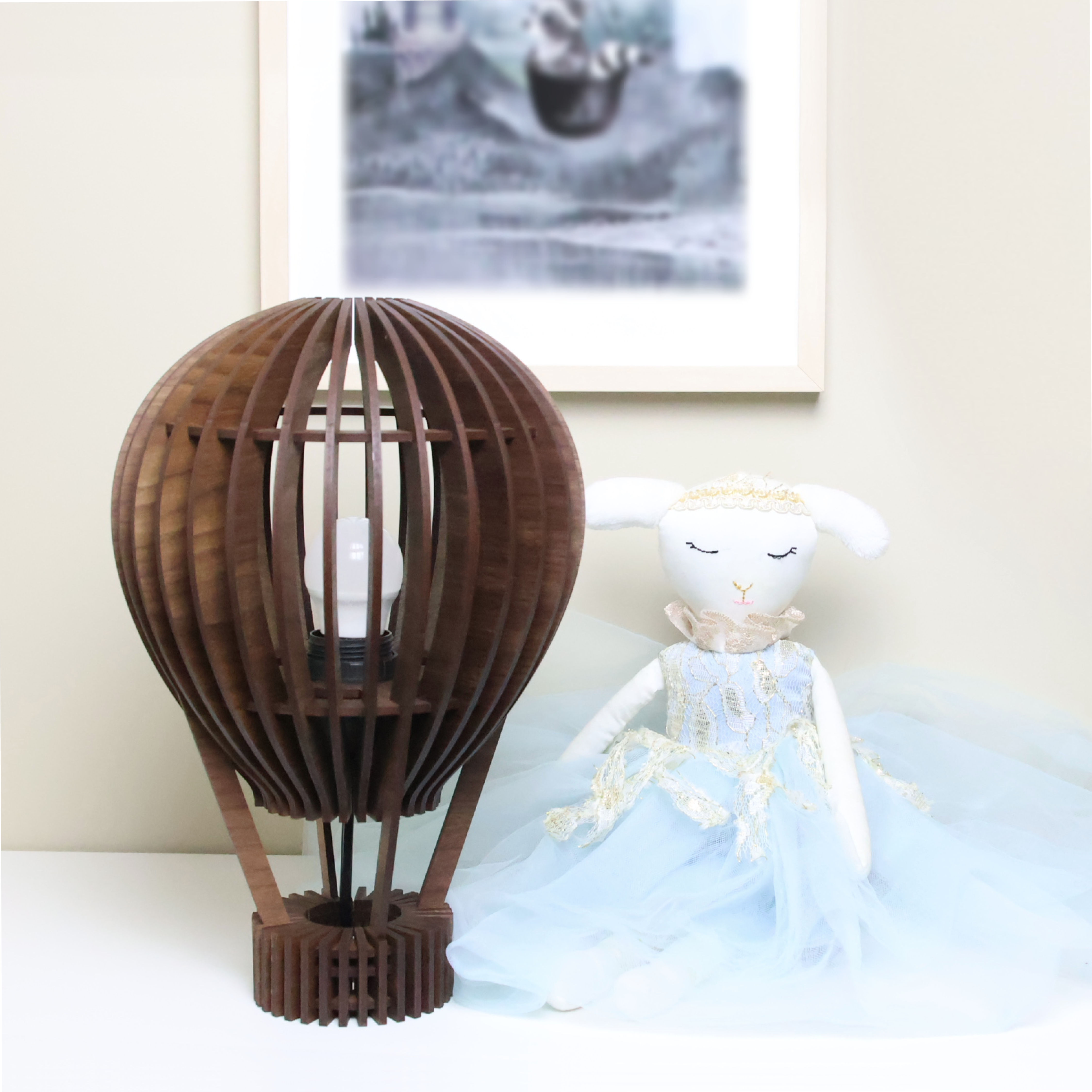 Spilelampe i valnøtt formet som en luftballong sammen med en blå bamse i front av bilde