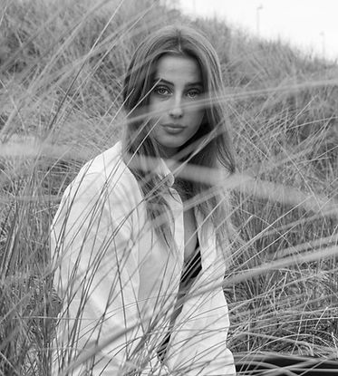 Zwart-wit portret van Luna op het strand met wind in het haar | Vrij werk fotografie met gevoel