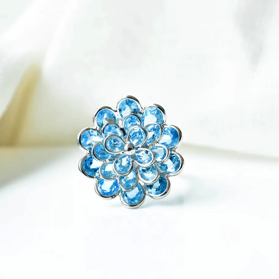 Floral sky blue topaz gemstone ring in sterling silver with layered petal design and bright blue stones