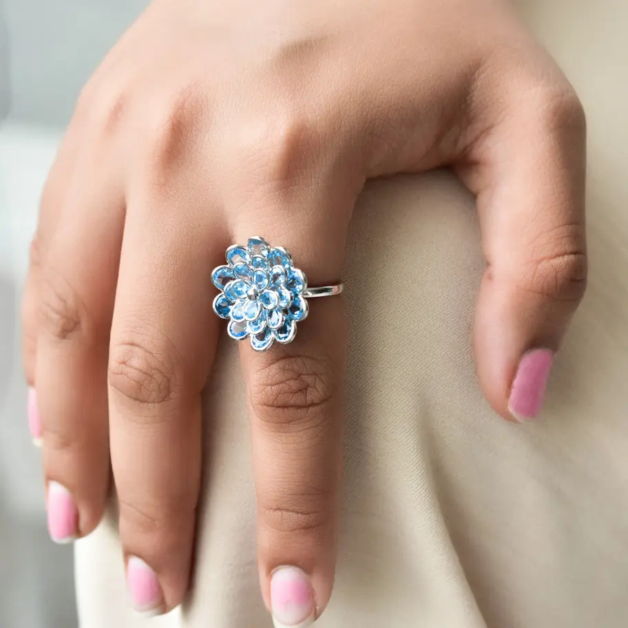Side view of blue topaz flower ring showing elevated cluster setting on sleek 925 silver band