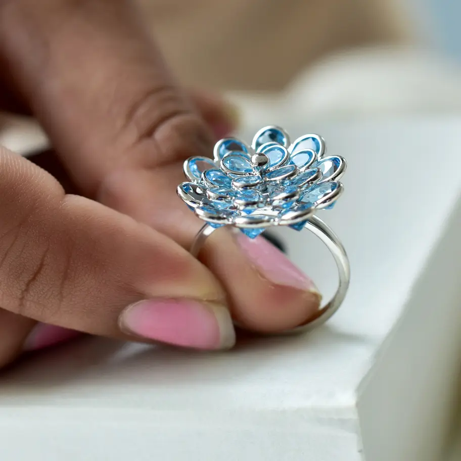 Side view of blue topaz flower ring showing elevated cluster setting on sleek 925 silver band
