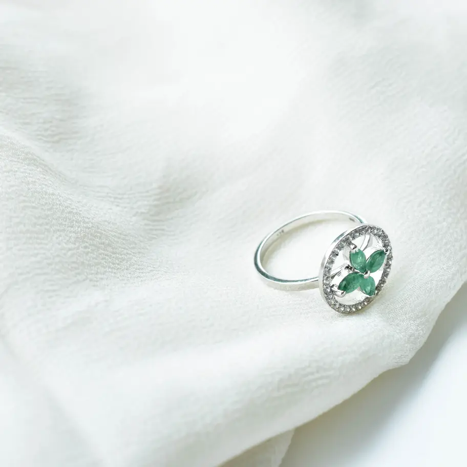Emerald green floral gemstone ring with American diamond accents in 925 sterling silver worn on hand, elegant statement jewel