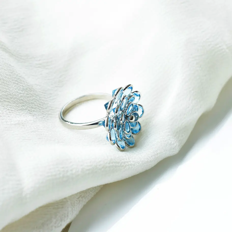 Side view of blue topaz flower ring showing elevated cluster setting on sleek 925 silver band