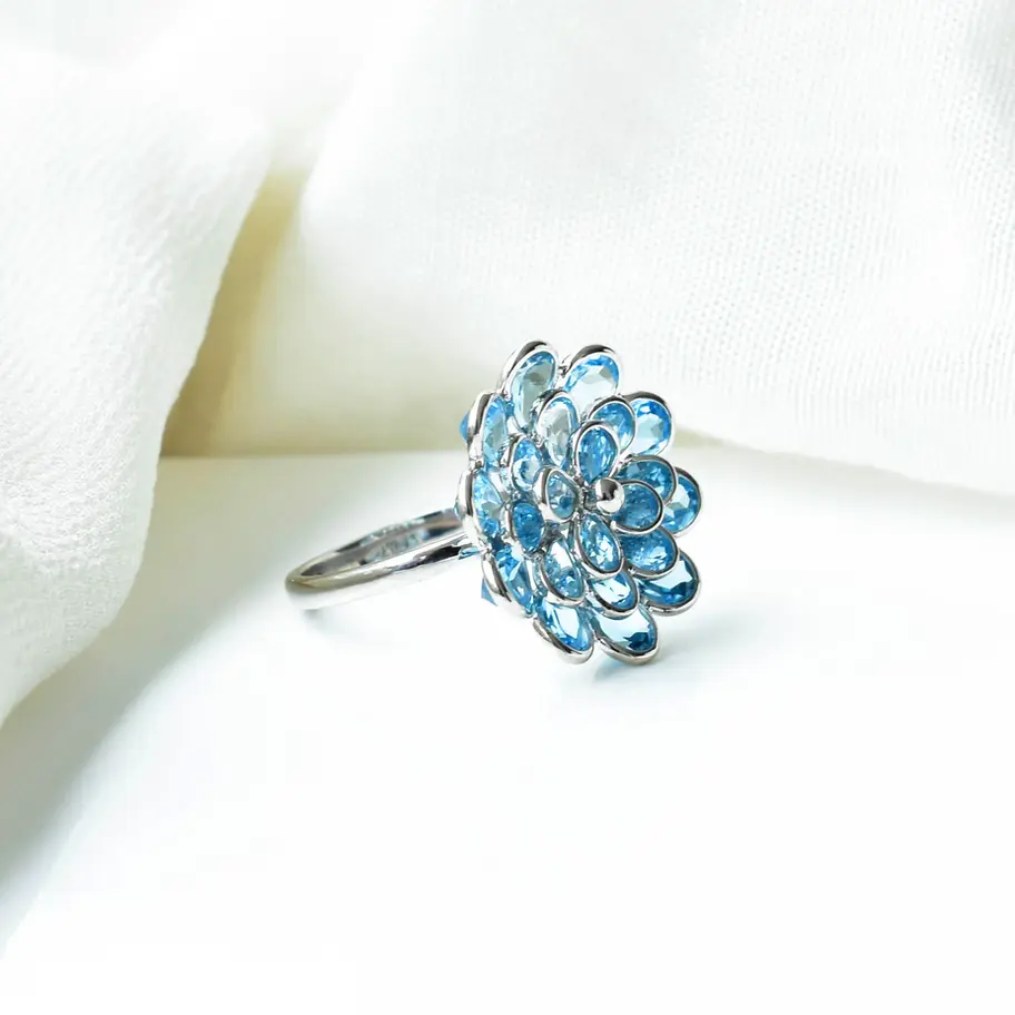 Side view of blue topaz flower ring showing elevated cluster setting on sleek 925 silver band