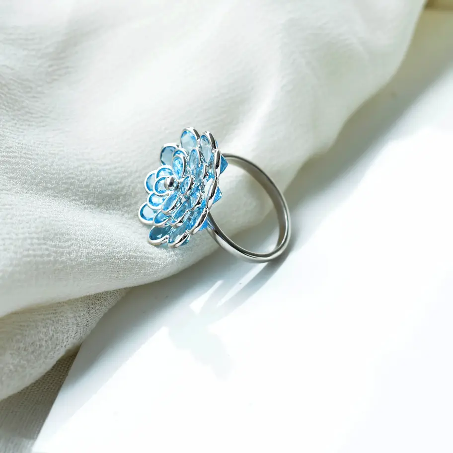 Side view of blue topaz flower ring showing elevated cluster setting on sleek 925 silver band