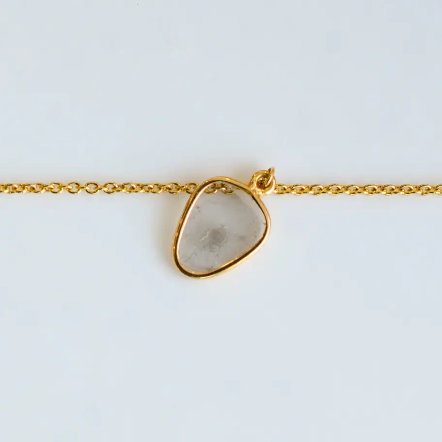 Macro view of natural diamond teardrop charm set in polished 18K gold bracelet