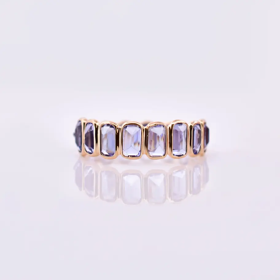 18K gold natural tanzanite eternity ring with baguette cut gemstones in a full eternity band design.