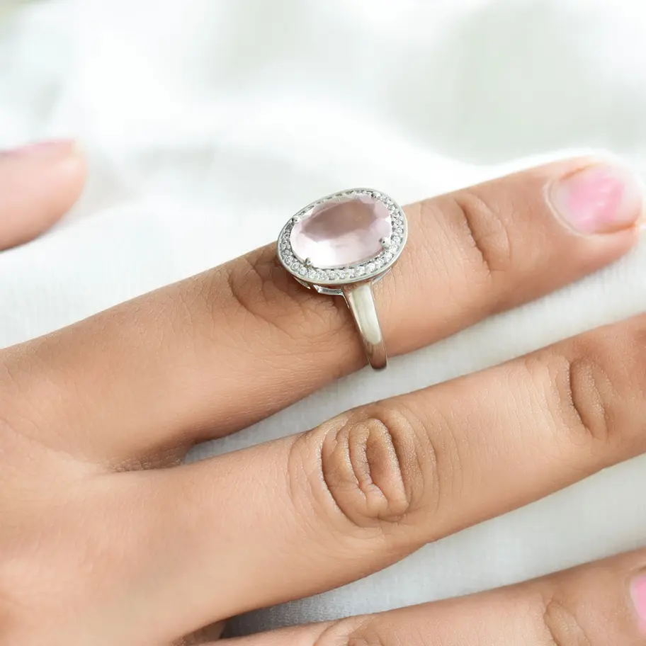 Shop this natural rose quartz ring in 925 sterling silver, featuring a soft blush pink oval gemstone surrounded by sparkling