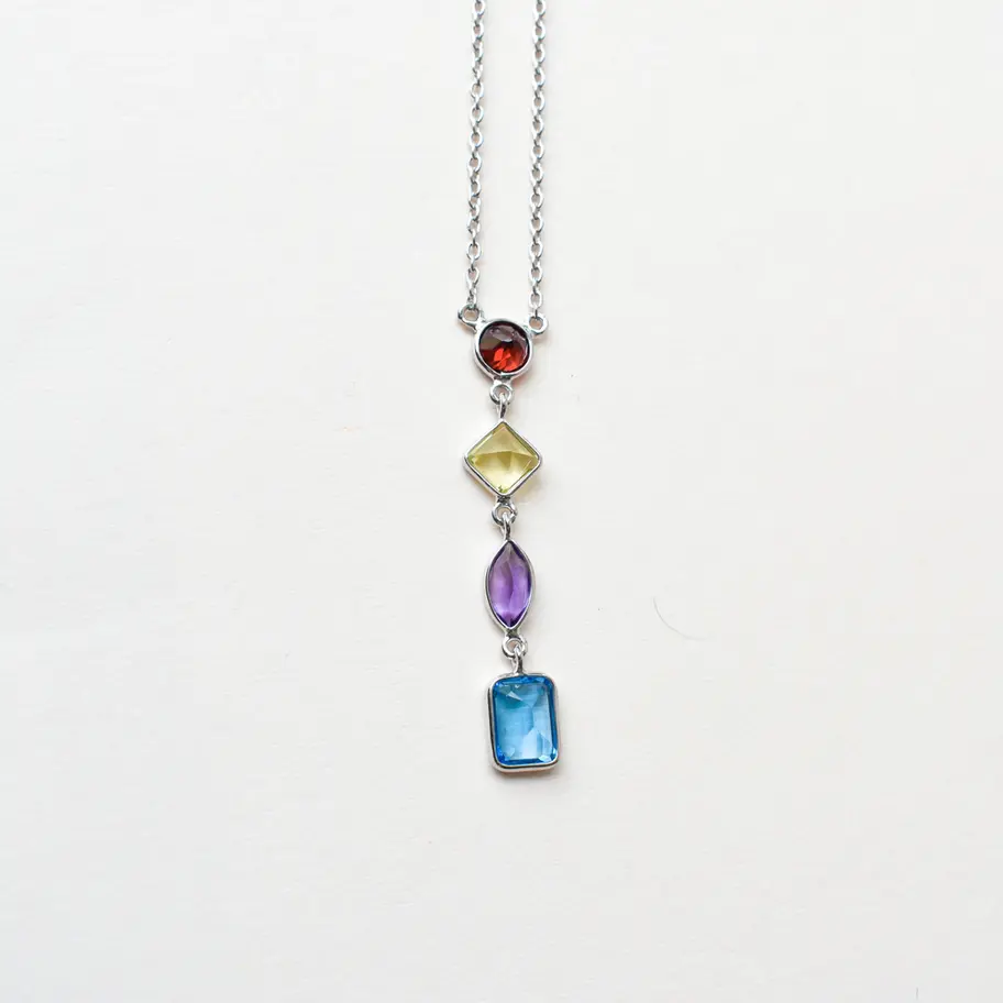 Multi gemstone necklace with garnet peridot amethyst topaz in silver Close-up of graduated bezel-set gemstones on drop neckla