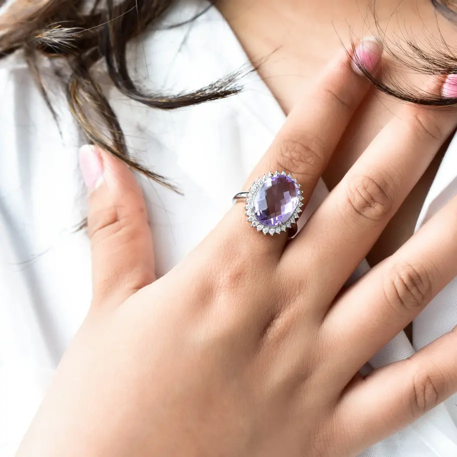 Oval amethyst gemstone ring with American diamond halo in 925 sterling silver worn on hand, elegant purple statement jeweller
