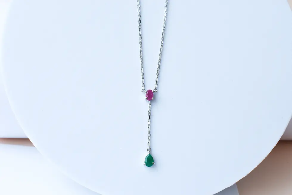 Ruby emerald necklace in sterling silver on white background Close-up of prong-set natural ruby and emerald gemstones Dainty
