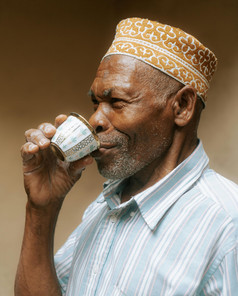 Zanzibari man smiling while drinking coffee at a local café, Stone Town, Zanzibar.