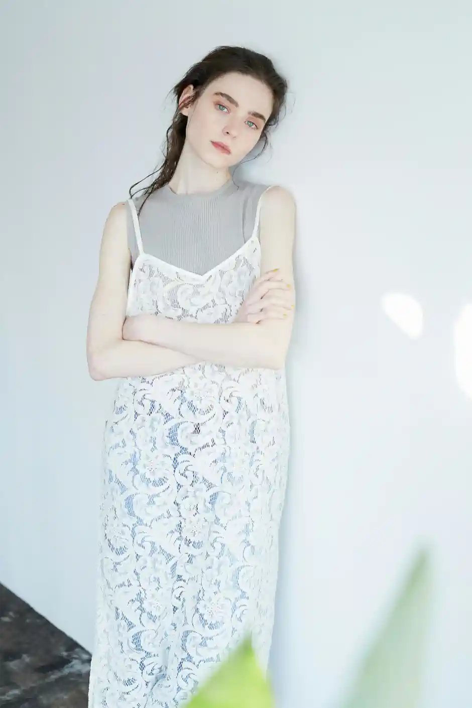 Woman wearing a delicate white lace dress layered over a soft grey top, expressing a gentle, romantic and understated feminine style.