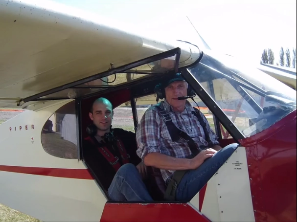 Stephanie’s father Donn in the cockpit of a light airplane with a companion, showing his adventurous spirit and joy.